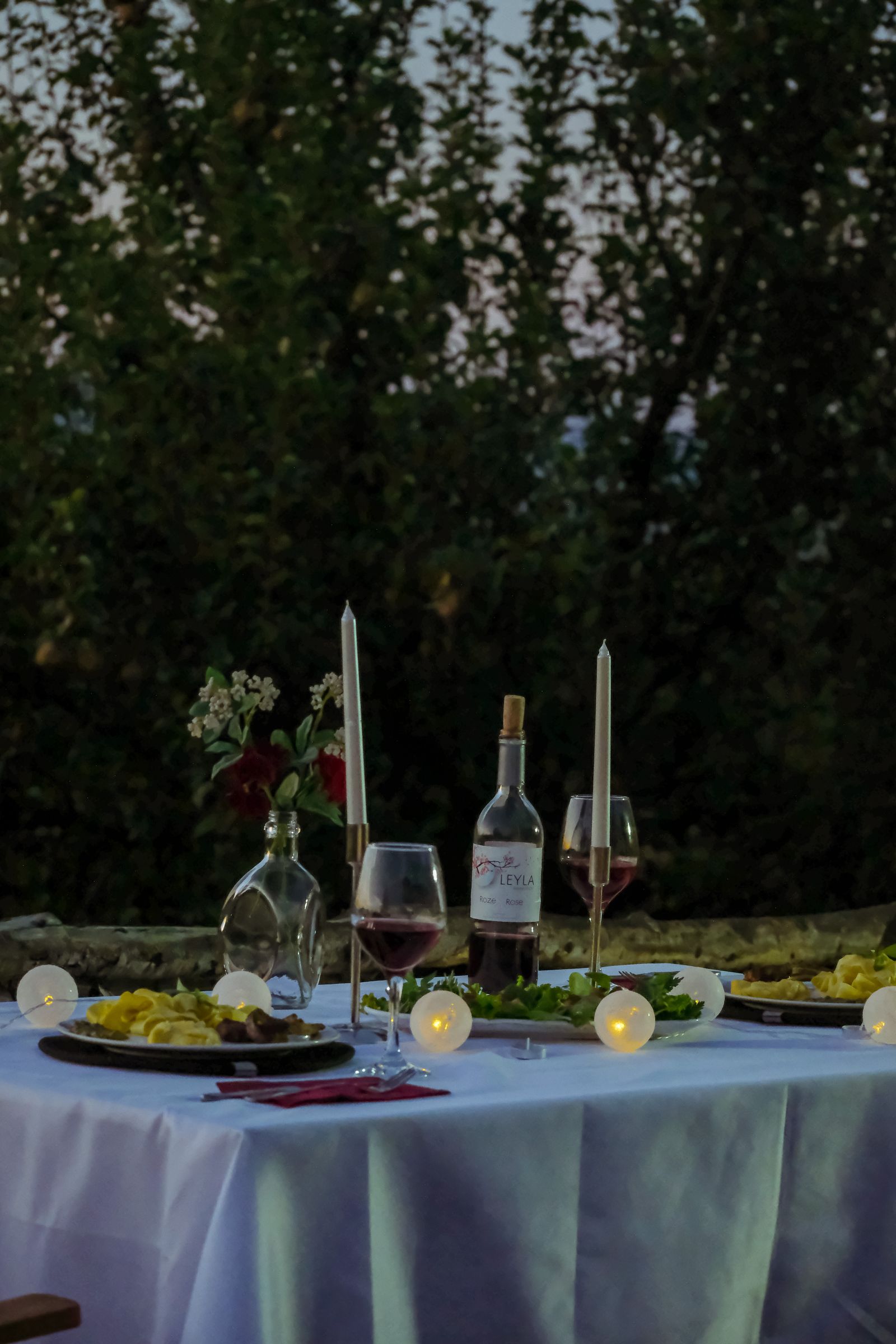 A candlelit table in a garden at dusk
